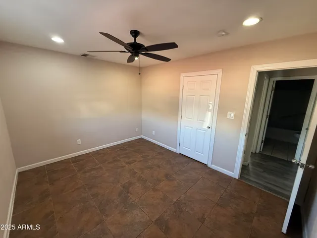 an empty room with a ceiling fan and window
