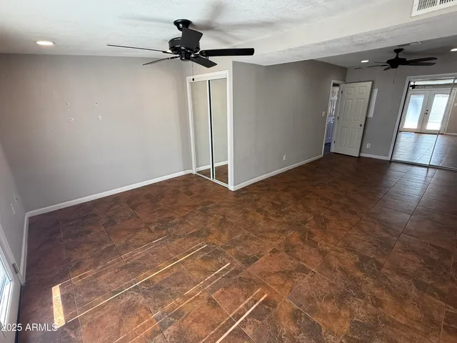 en empty room with wooden floor and fan