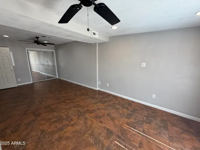 an empty room with a ceiling fan and window
