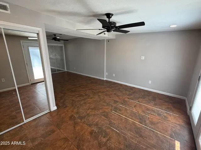 an empty room with wooden floor fan and windows