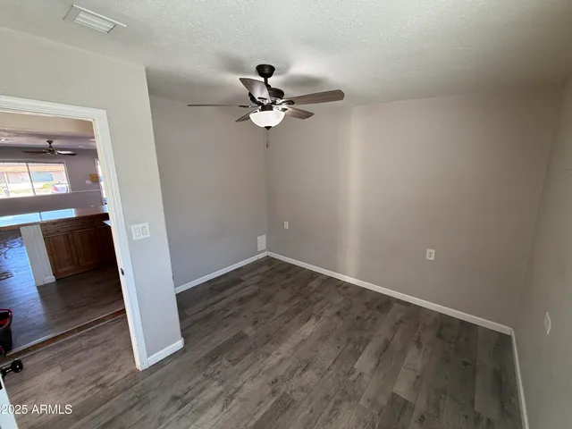 an empty room with wooden floor fan and windows