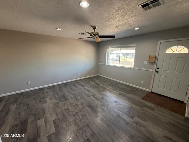 an empty room with wooden floor cabinet and windows