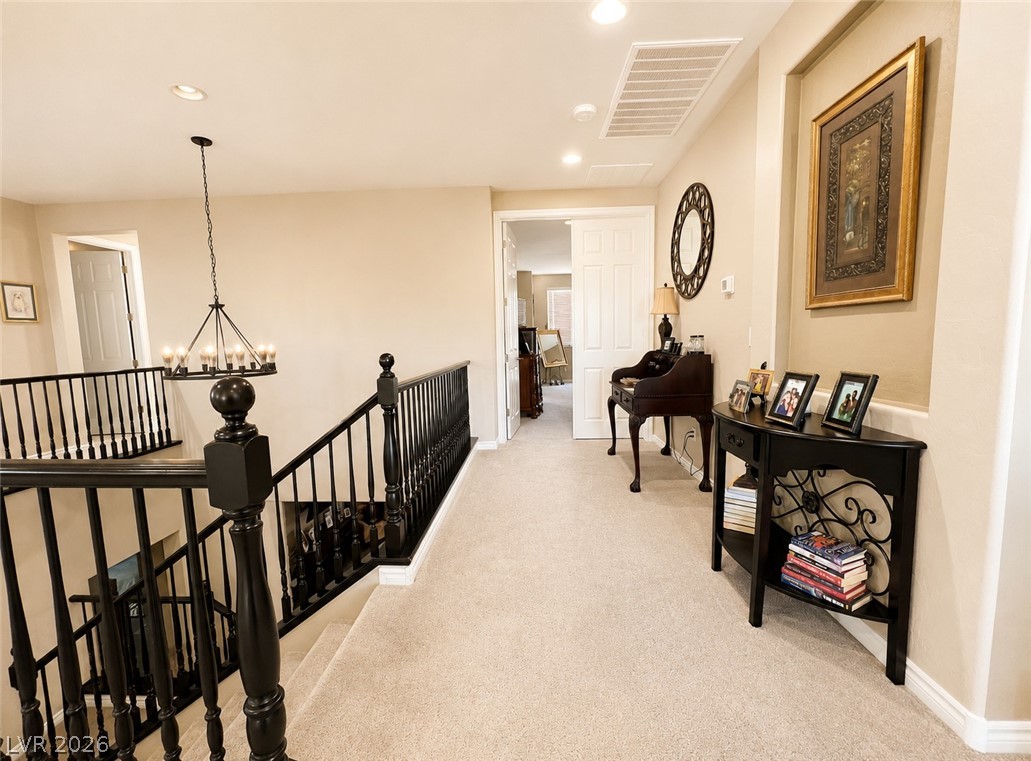 9724 University Ridge Avenue Las Vegas, NV 89149 - Photo 42 of 61 A graceful staircase with dark wood balusters leads to an upper hallway with soft carpeting and warm wall tones.