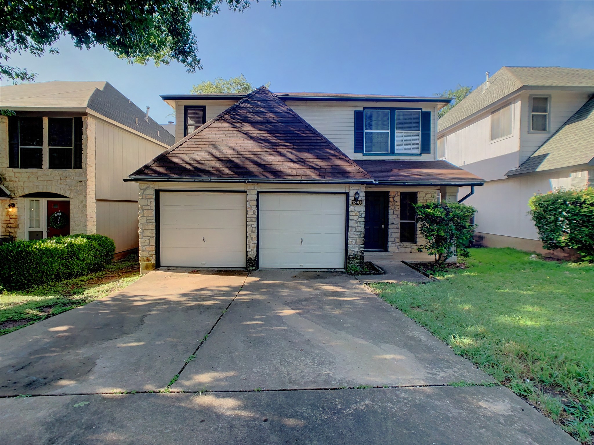 Traditional home featuring stone siding, driveway, a front yard, and an attached garage