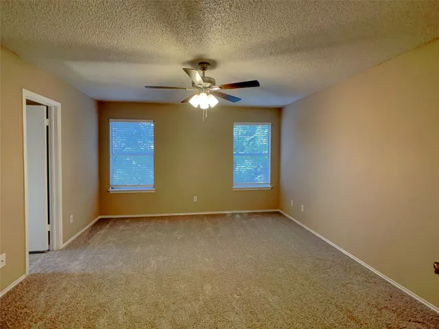 an empty room with windows and fan