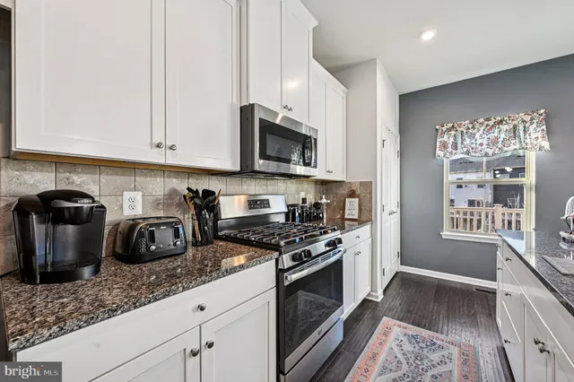 a kitchen with stainless steel appliances granite countertop a refrigerator a stove and a sink with wooden floor