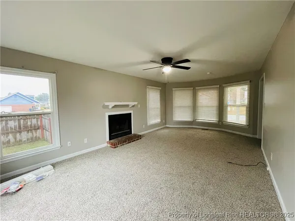 an empty room with windows and fireplace