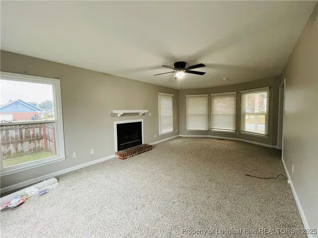 an empty room with windows and fireplace