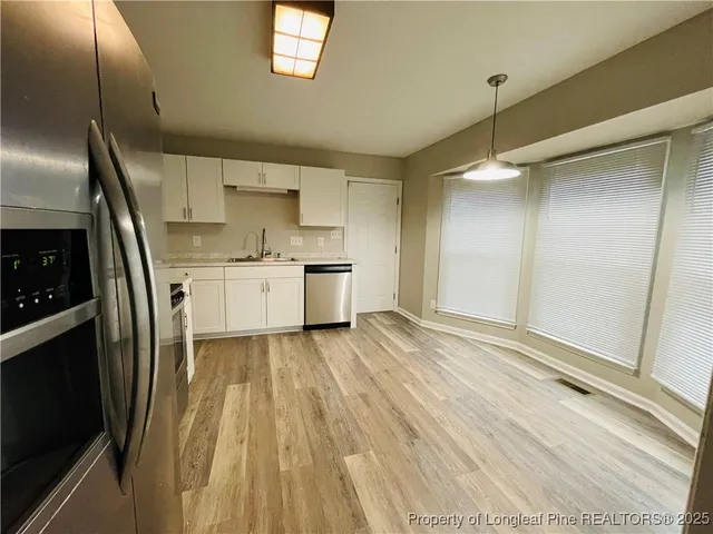 a kitchen with stainless steel appliances a refrigerator and a wooden floor