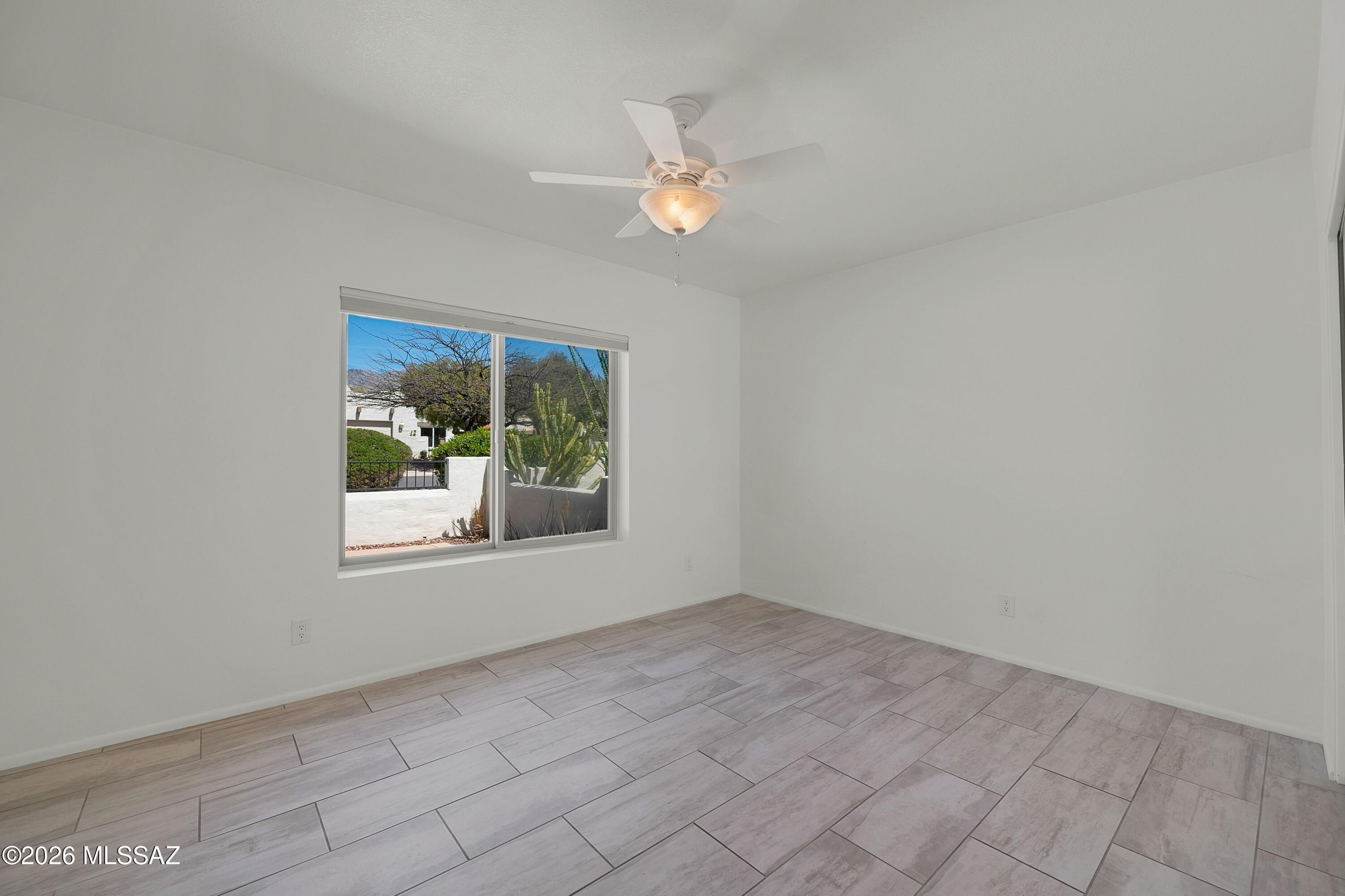 7408 East Wandering Road Tucson, AZ 85750 - Photo 19 of 25 an empty room with a chandelier fan and windows