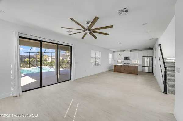 a view of empty room with floor to ceiling window and ceiling fan
