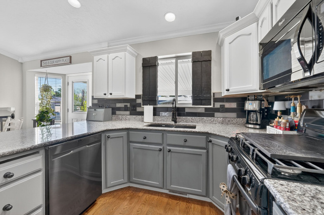 415 East 400 North Santaquin, UT 84655 - Photo 9 of 39 Kitchen featuring two-tone cabinetry with white upper and gray lower cabinets, speckled countertops, a dark tile backsplash, and wood-finish flooring