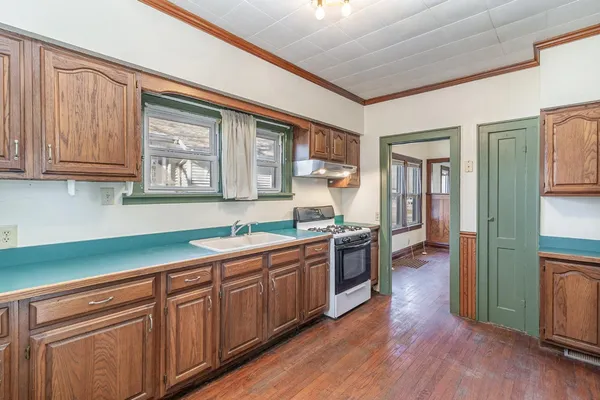 a view of a livingroom with wooden floor staircase and a kitchen space