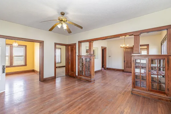 a view of an empty room with wooden floor and a window