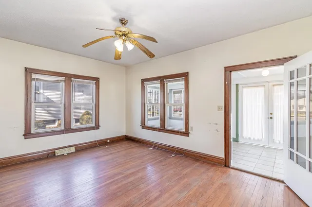 a view of empty room with wooden floor and fan