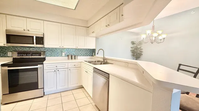 a kitchen with stainless steel appliances granite countertop a sink a stove a microwave oven with white cabinets