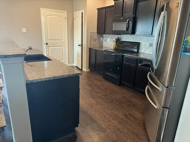 a kitchen with granite countertop a refrigerator and a sink
