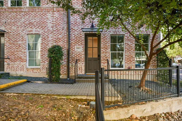 a view of a brick house with large windows and plants