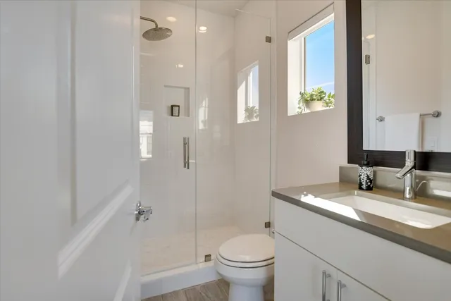 a bathroom with a granite countertop sink a toilet a mirror and shower