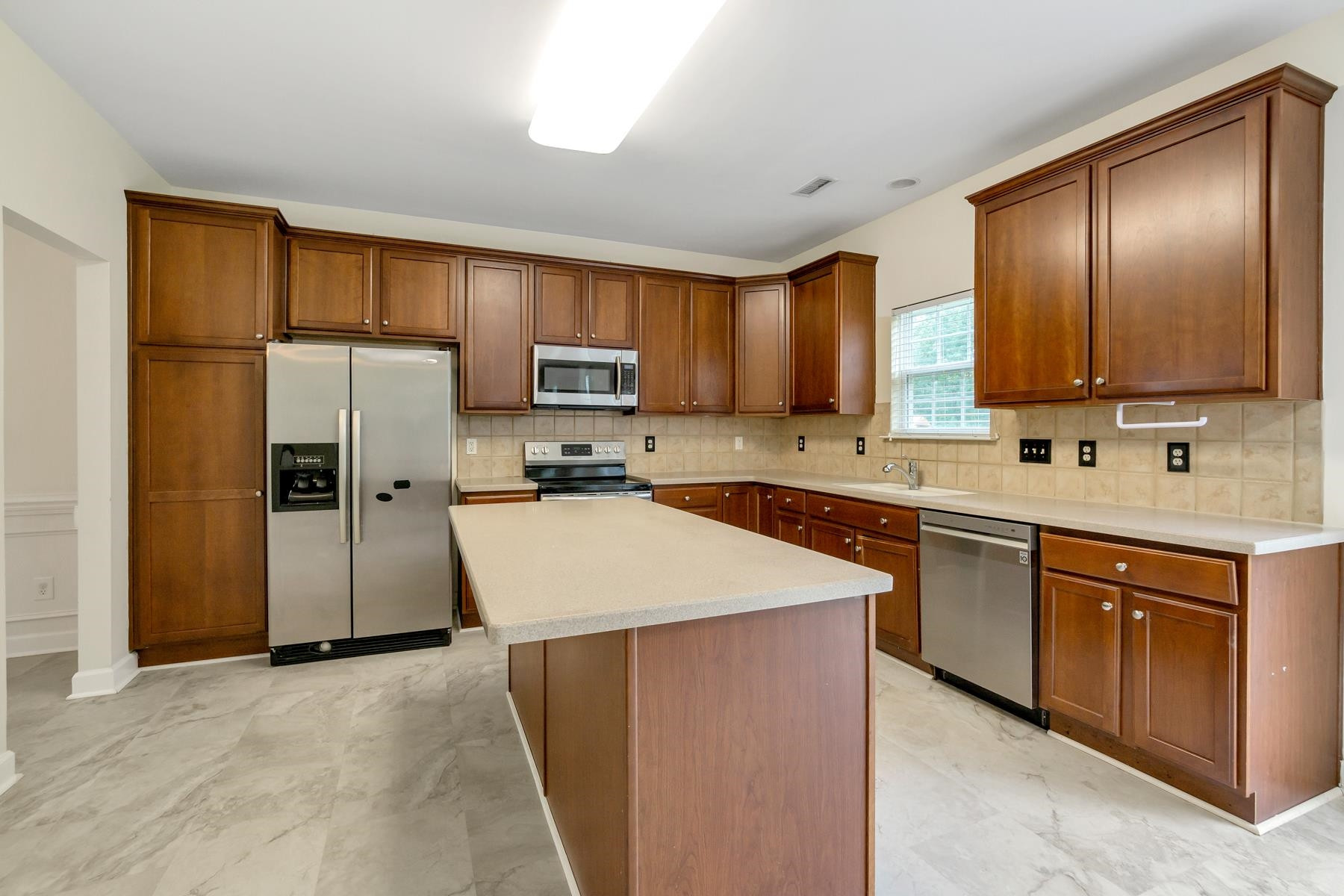6316 Sparkling Brook Drive Raleigh, NC 27616 - Photo 13 of 44 a kitchen with kitchen island granite countertop wooden cabinets a refrigerator stove a sink and dishwasher