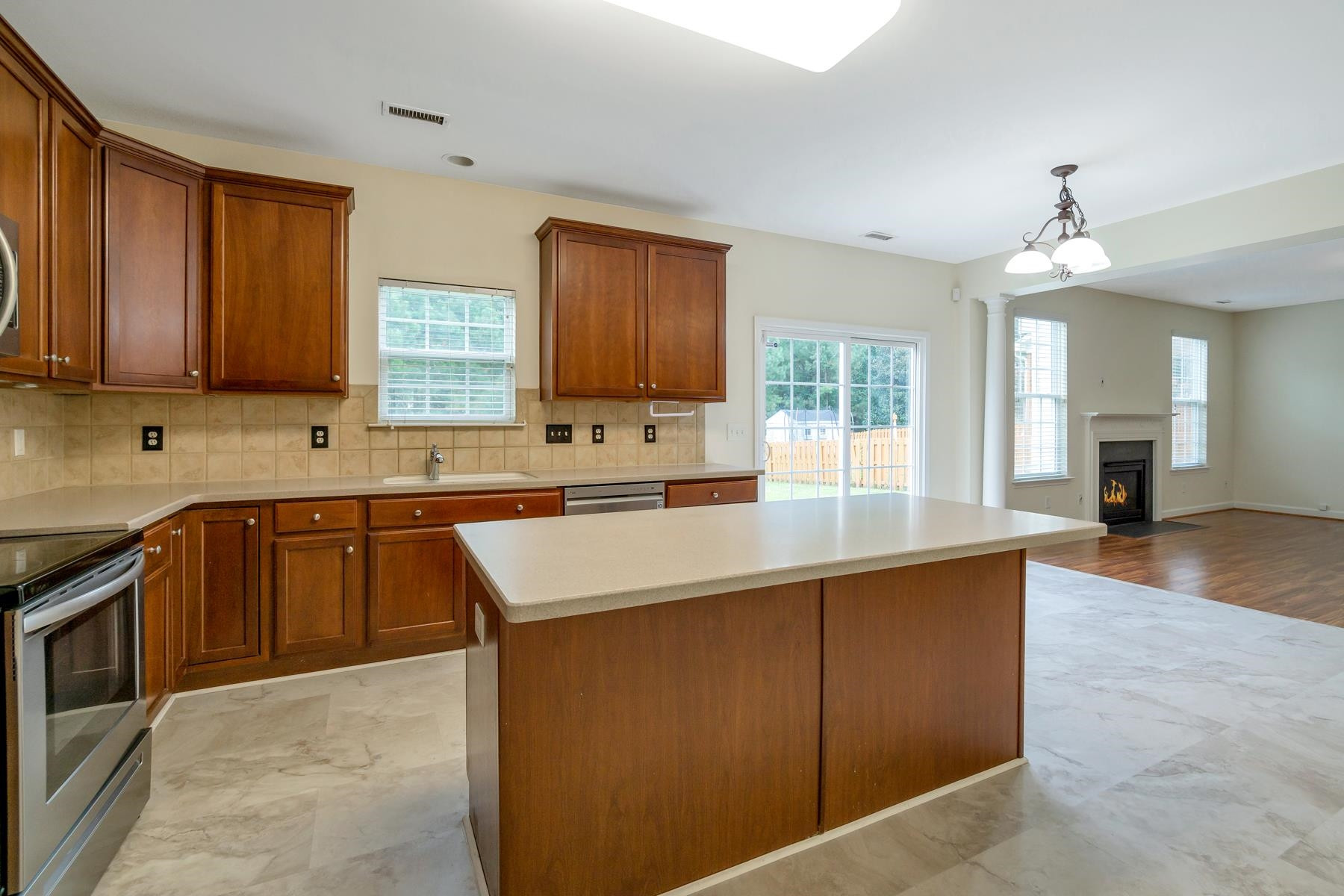 6316 Sparkling Brook Drive Raleigh, NC 27616 - Photo 14 of 44 a kitchen with kitchen island granite countertop a stove top oven a sink a counter space and cabinets