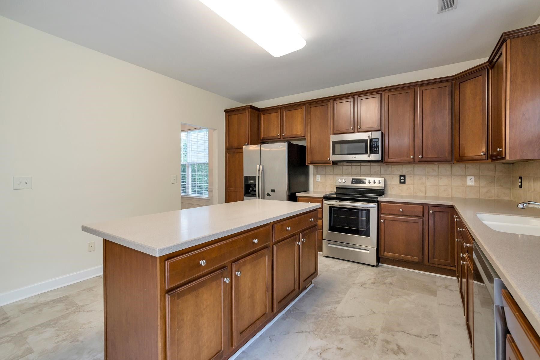 6316 Sparkling Brook Drive Raleigh, NC 27616 - Photo 15 of 44 a kitchen with stainless steel appliances granite countertop a stove a sink and a refrigerator with wooden cabinets