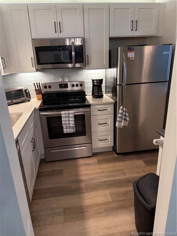 1225 Northwest 21st Street Northwest, Unit 2504 Stuart, FL 34994 - Photo 5 of 17 a kitchen with granite countertop a refrigerator stove and white cabinets