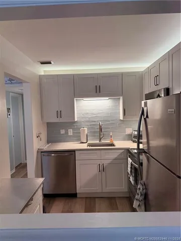 a kitchen with stainless steel appliances a sink a stove a refrigerator and cabinets