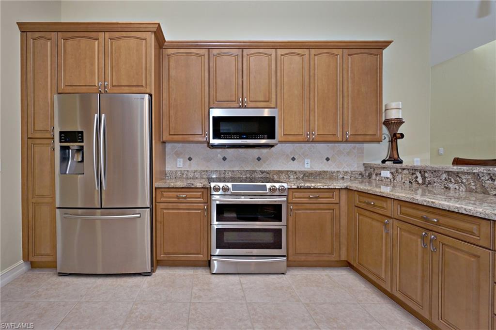 8007 Tiger Lily Drive Naples, FL 34113 - Photo 11 of 32 a kitchen with appliances a refrigerator and a sink
