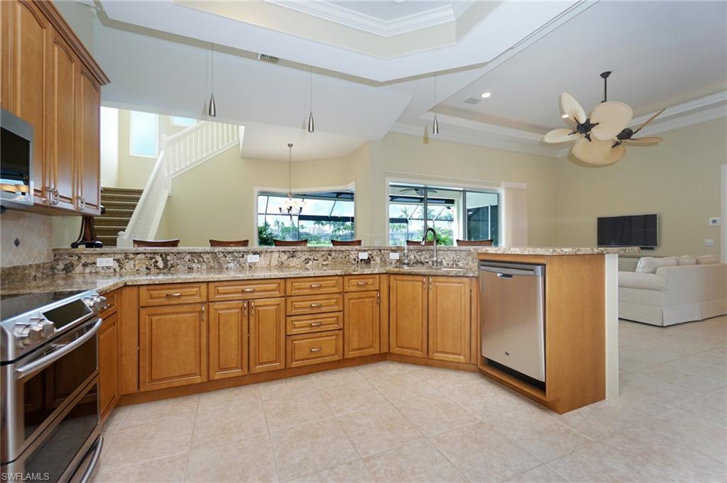 8007 Tiger Lily Drive Naples, FL 34113 - Photo 32 of 32 a large white kitchen with stainless steel appliances granite countertop a stove a sink dishwasher and white cabinets with wooden floor