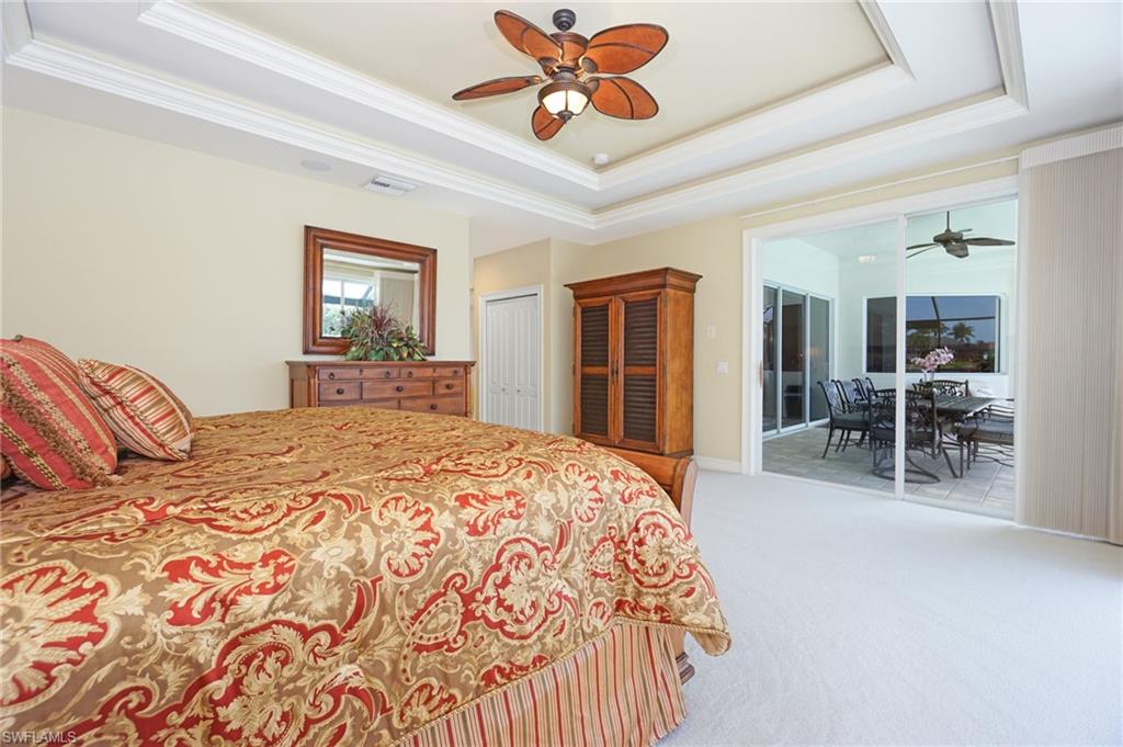 8007 Tiger Lily Drive Naples, FL 34113 - Photo 15 of 32 a bedroom with a large bed and a chandelier