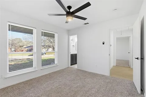 an empty room with windows and ceiling fan