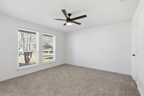 an empty room with windows and ceiling fan