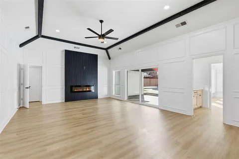 a view of an empty room with wooden floor and a ceiling fan