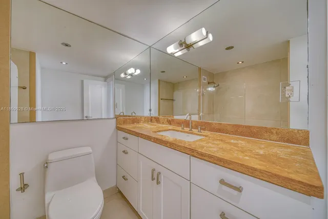 a bathroom with a granite countertop sink a toilet and a shower