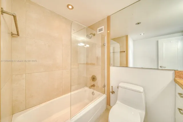 a bathroom with a bathtub shower sink vanity and toilet
