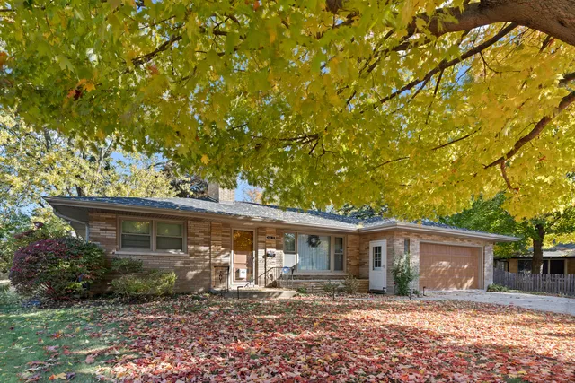 a front view of a house with yard tree and wooden fence