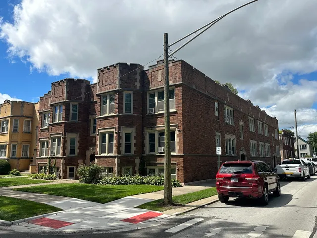 a red car parked in front of a brick house