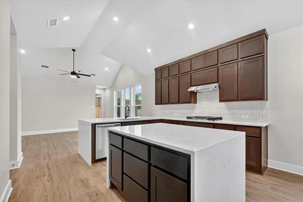 a kitchen with stainless steel appliances a sink stove and wooden floor