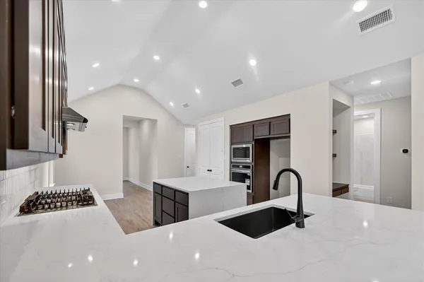 a large white kitchen with stainless steel appliances a sink and a stove top oven