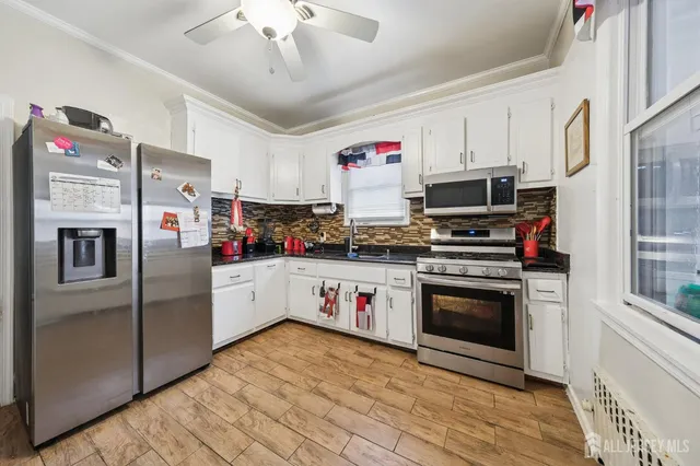 a kitchen with stainless steel appliances a refrigerator a stove and white cabinets
