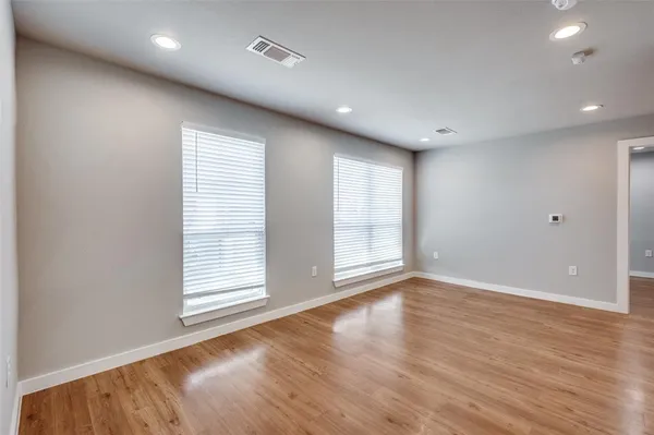 an empty room with wooden floor and windows