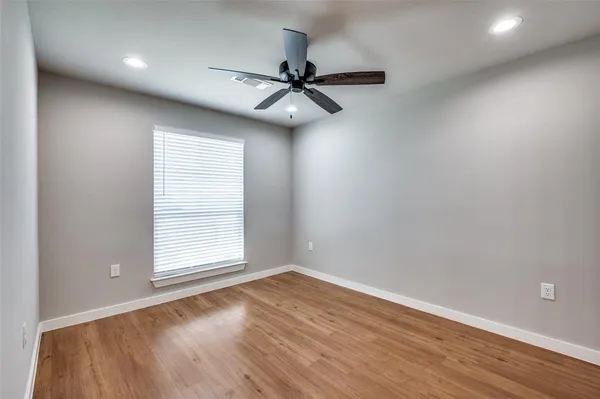an empty room with wooden floor fan and windows