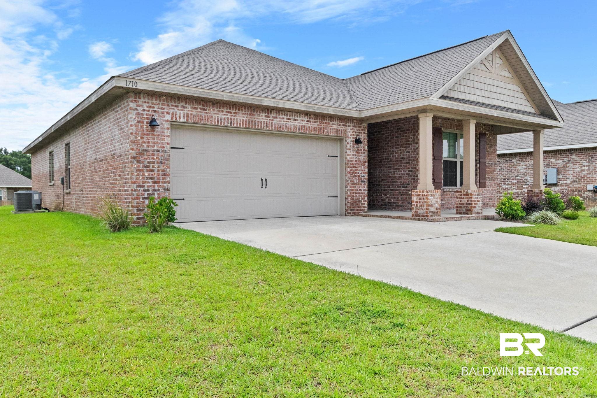 1710 Grouse Street Foley, AL 36535 - Photo 9 of 76 Brick exterior featuring a gabled roofline, concrete driveway, and covered front entry with columns
