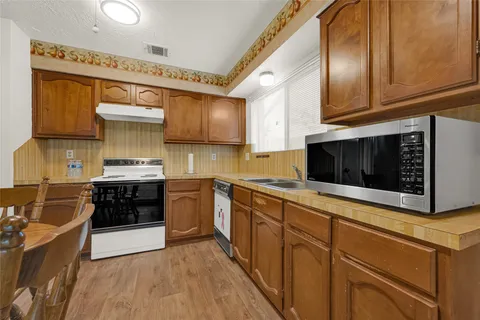 a kitchen with stainless steel appliances granite countertop a stove a sink and a microwave