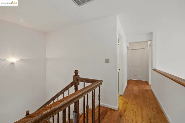 a view of a hallway with wooden floor and stairs