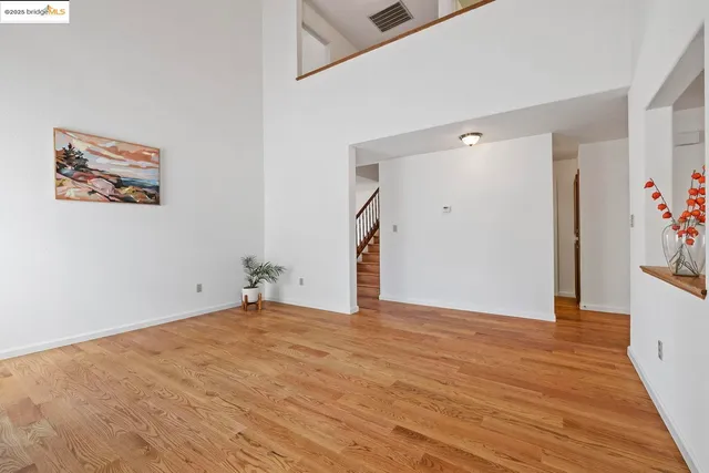 a view of an empty room with wooden floor and potted plant