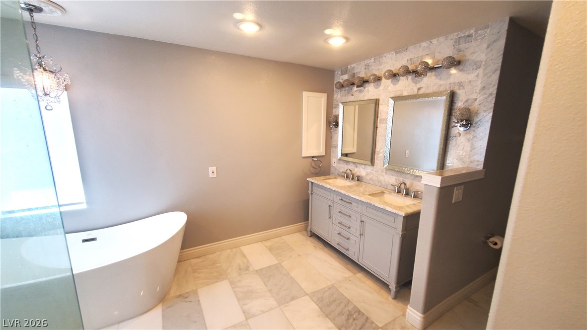 7903 Dell Ridge Avenue Las Vegas, NV 89179 - Photo 10 of 20 Luxurious bathing space showcasing a graceful freestanding tub and a spacious dual-sink vanity.