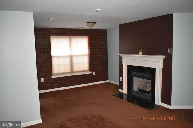 a view of an empty room with a fireplace and a window