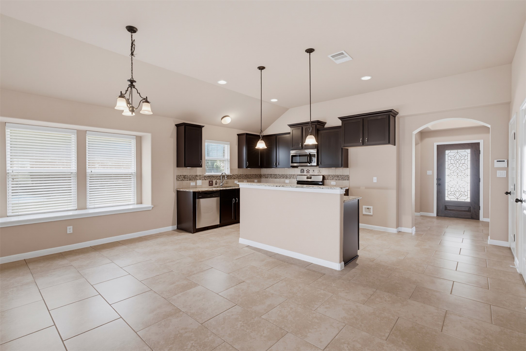 6033 Roma Street Round Rock, TX 78665 - Photo 5 of 28 Clean tile flooring and a central breakfast bar anchor this open-concept kitchen space.